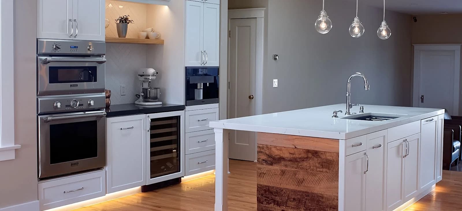 A bright kitchen with a white island, pendant lights, and built-in appliances.