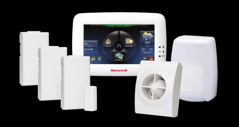 A Honeywell alarm touchscreen and a group of white security sensors.